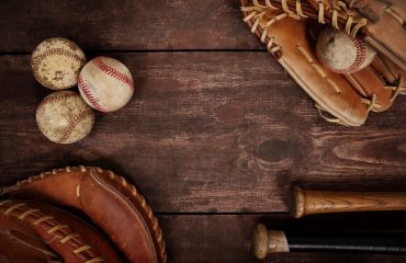Image of baseballs, gloves and bats on a wooden background