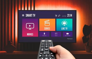 Hand holding remote control pointing at a Smart TV