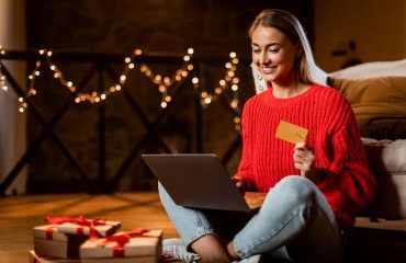 Woman holiday shopping on laptop with credit card in hand