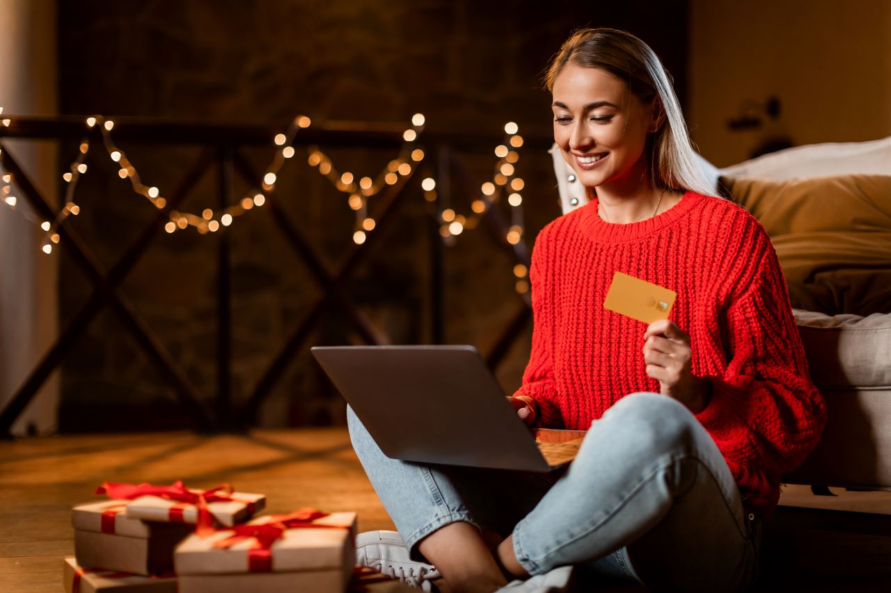 Woman holiday shopping on laptop with credit card in hand