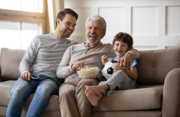 Fathes and Son on couch watching TV while laughing