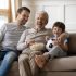 Fathes and Son on couch watching TV while laughing
