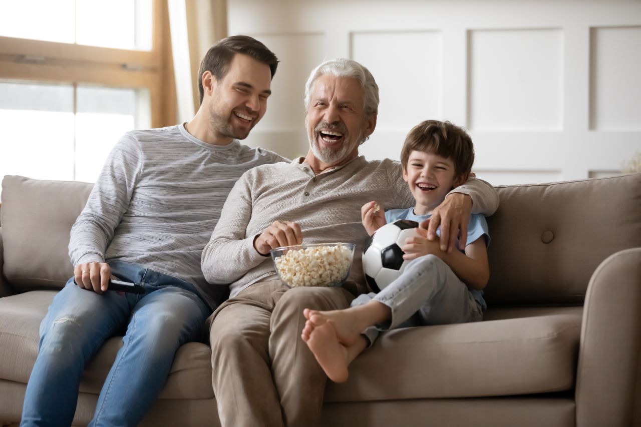 Fathes and Son on couch watching TV while laughing